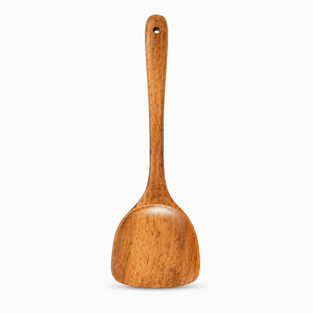 Détail du bout plat de la spatule cuisine bois glissant délicatement sur une surface antiadhésive