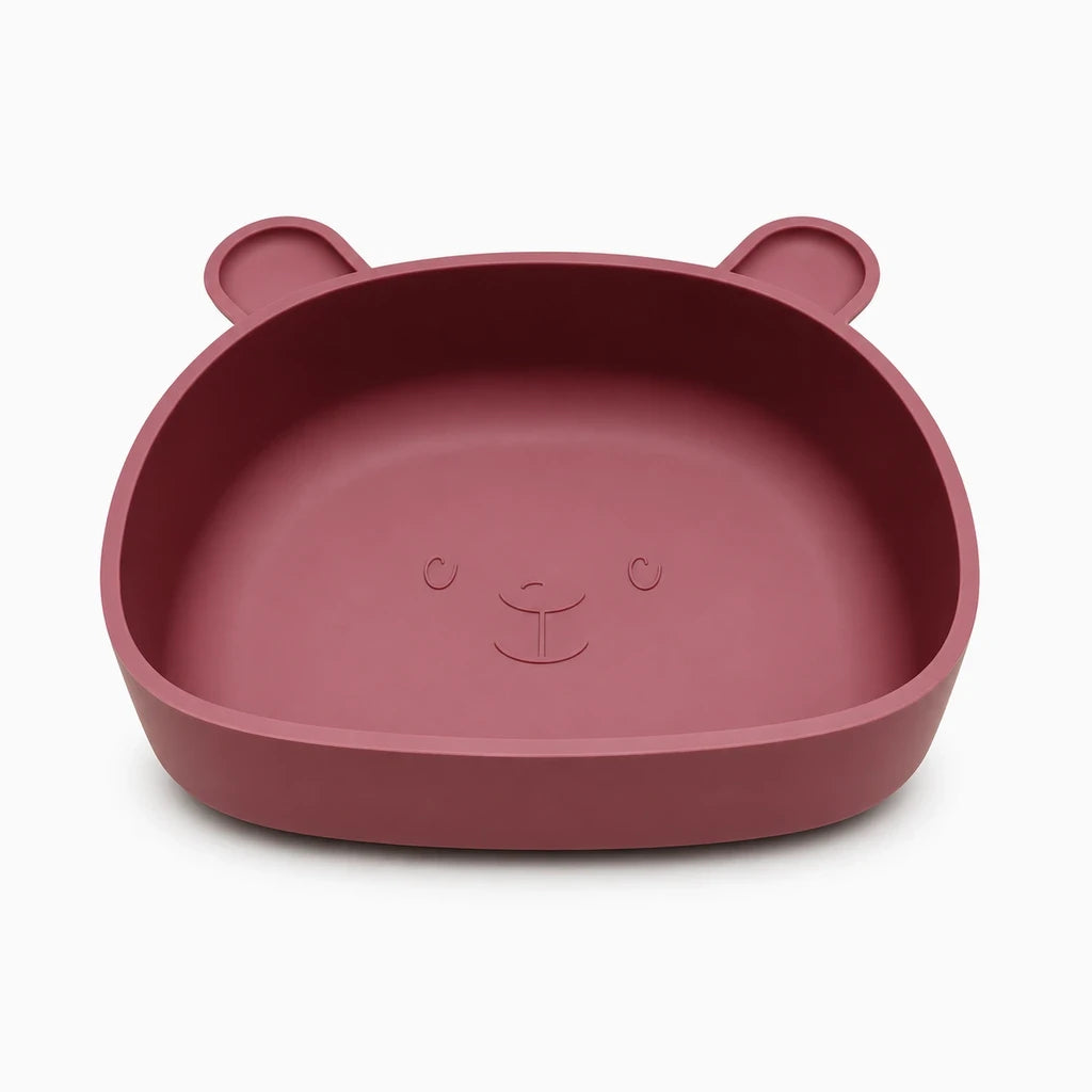 Assiette silicone bébé ronde dans les mains d'un enfant en train de manger