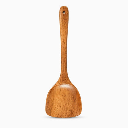 Détail du bout plat de la spatule cuisine bois glissant délicatement sur une surface antiadhésive